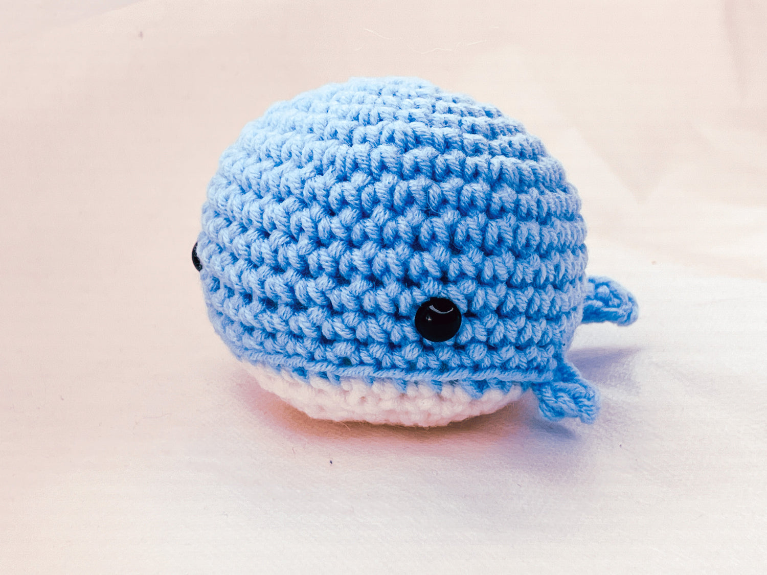 whale crochet plushie, black safety eyes, blue top white bottom. 